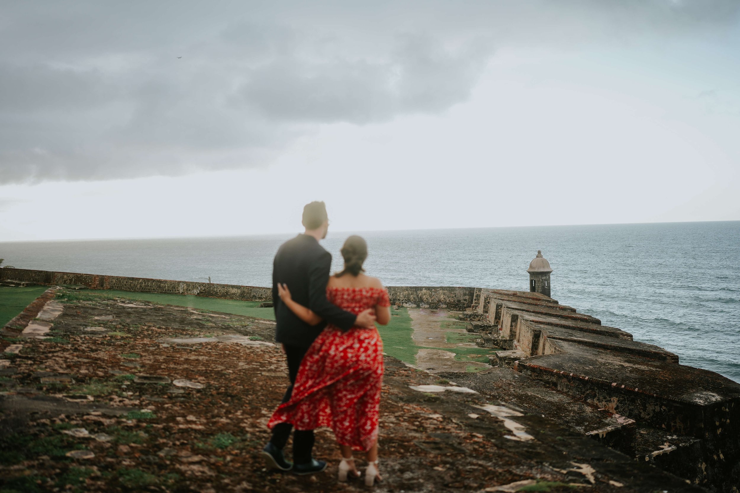 Engagement photos in Old San Juan. Couple looks off into the distance of the Old San Juan architecture