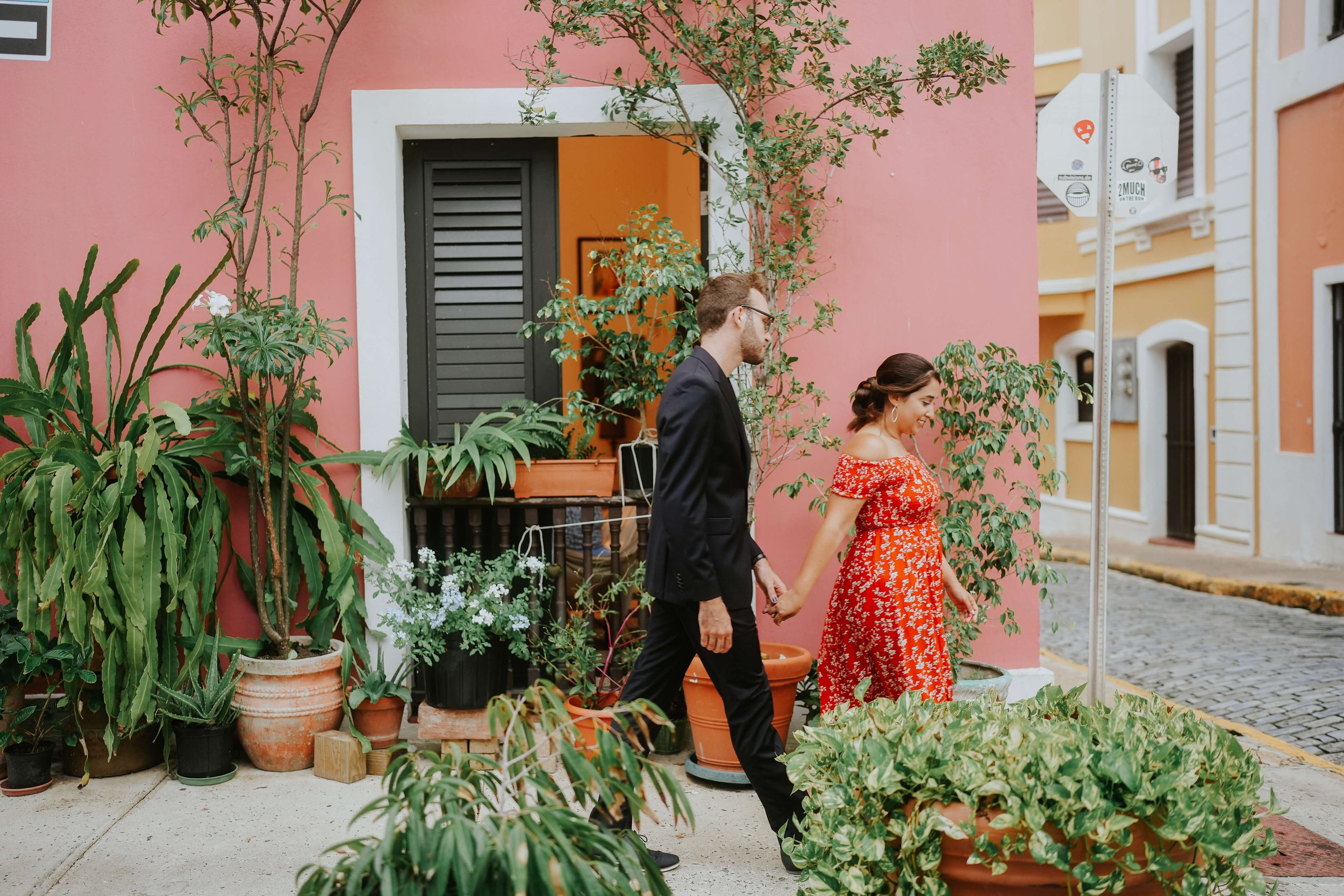 A couple walk hand in hand through the colorful streets of San Juan