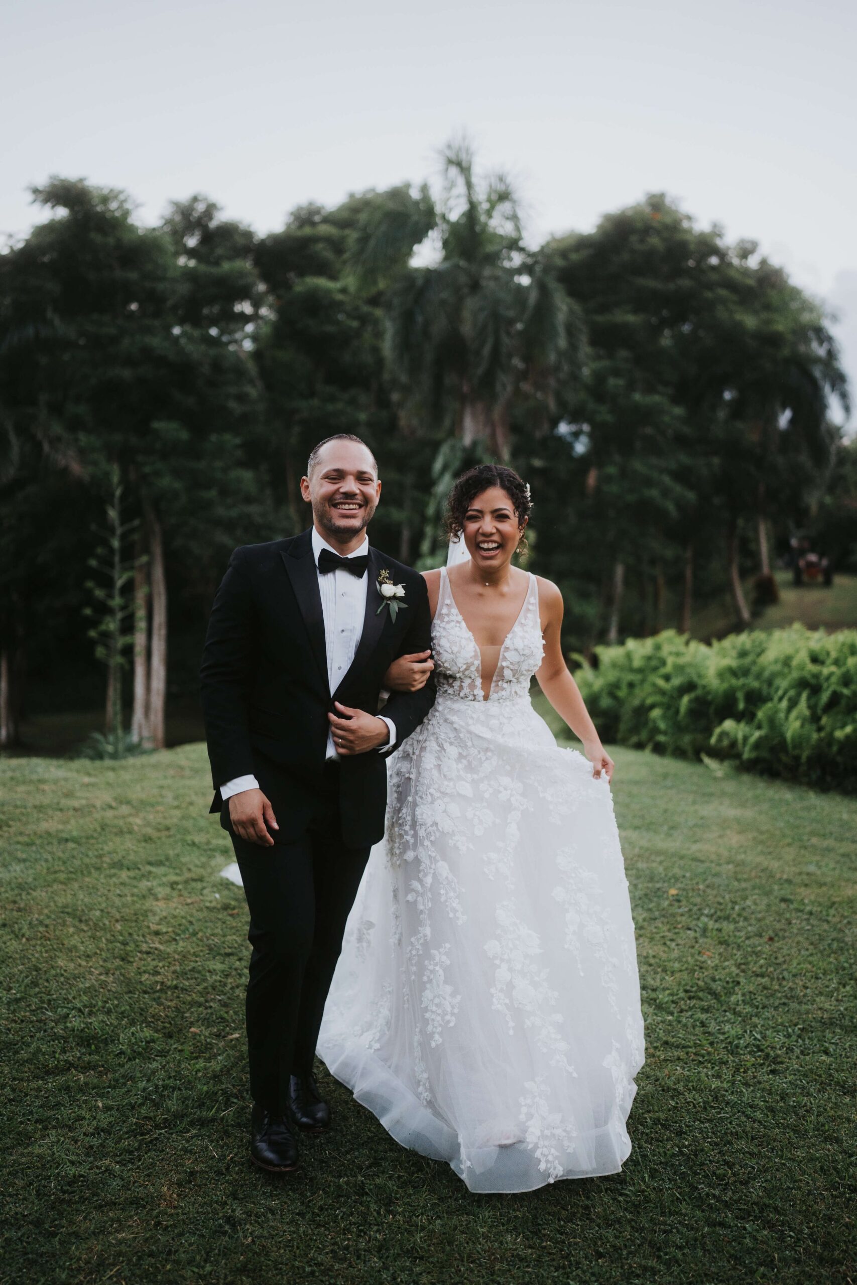 Bride and groom walk hand in hand, laughing.