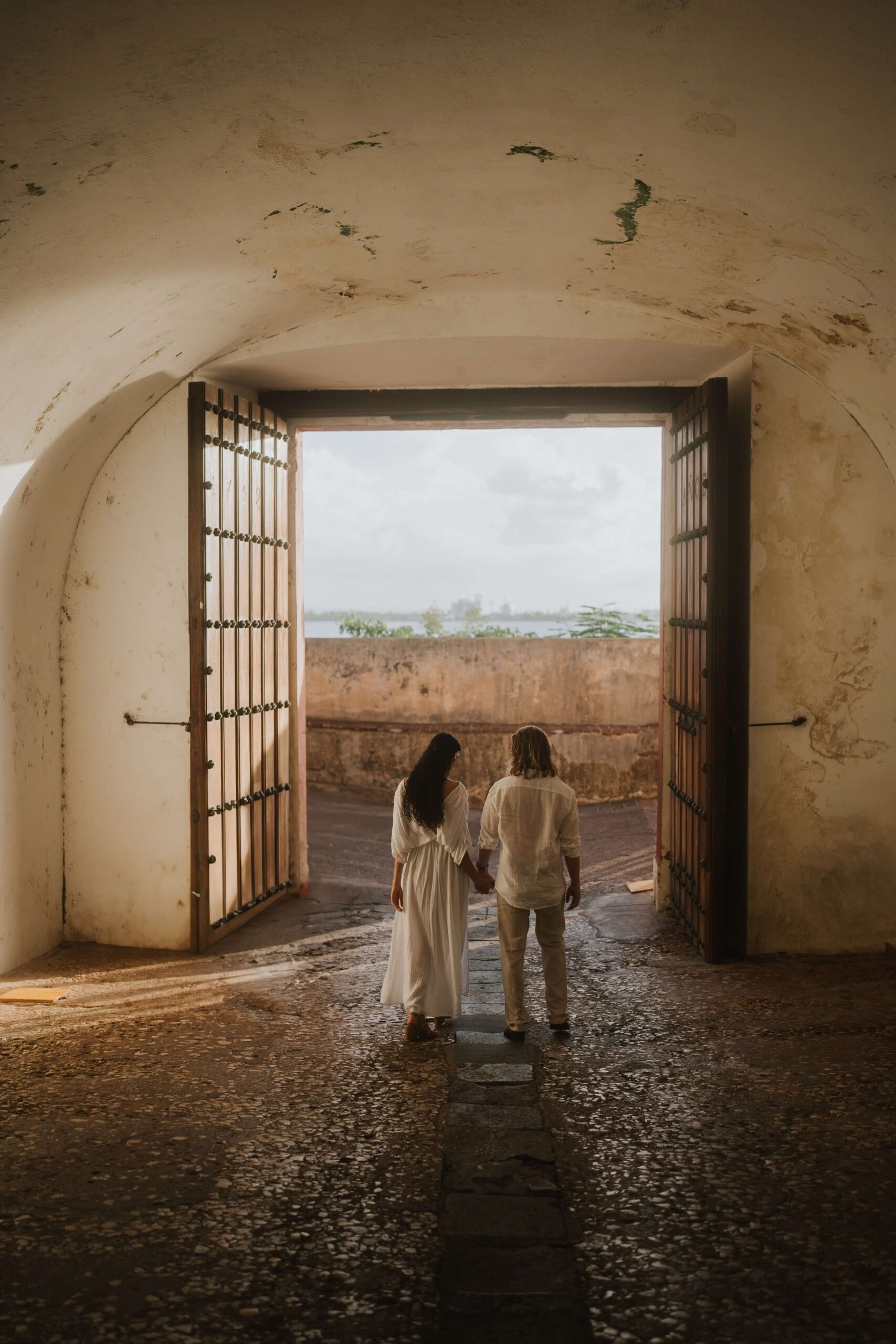 Engagement photos in Old San Juan. Couple walk hand in hand.